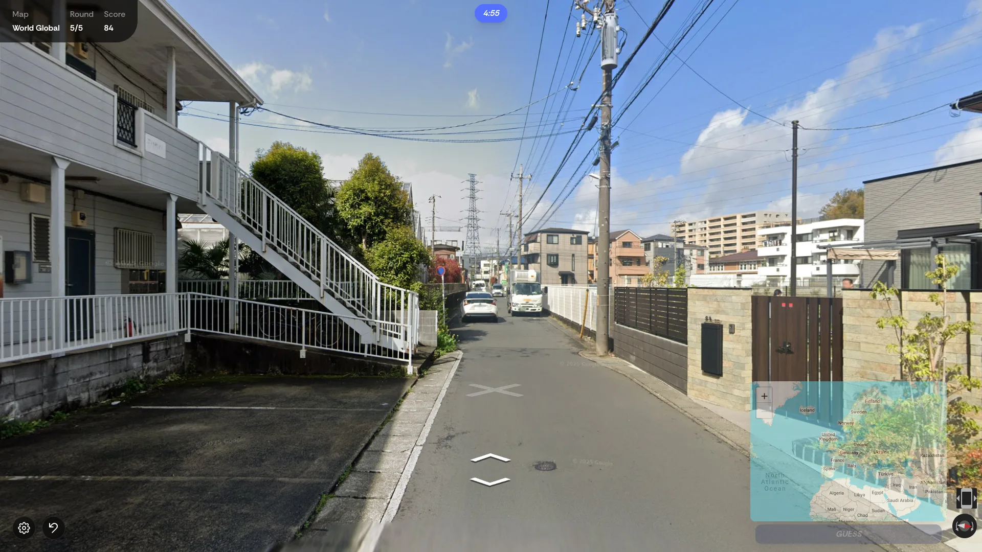 A narrow residential street lined with power lines, looking for clues to the country